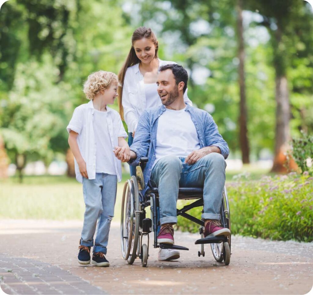 Young man in a wheelchair with his family in the park supported by MediStays hospital accommodation.